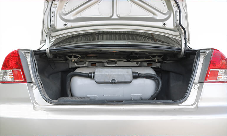 Carro sedã prata com cilindro de GNV cinza no porta malas 
